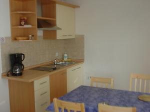 a kitchen with a sink and a table with chairs at Apartments Kuća Grško in Selce