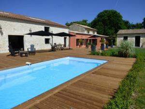 a swimming pool in a yard with a wooden deck at La Grange d'Aunis in Aigrefeuille-dʼAunis