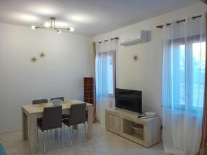 een woonkamer met een eettafel en een televisie bij CORTE Apartment in Murano