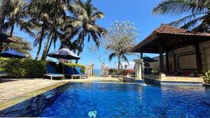 a swimming pool with blue chairs and palm trees at Nusa Indah Candidasa in Candidasa