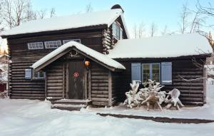 una cabaña de madera en la nieve con un grupo de personas fuera en Vemdalsskalsgården en Vemdalen