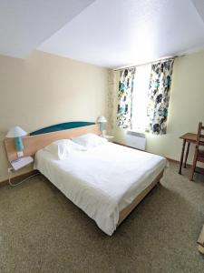 Un dormitorio con una gran cama blanca y una ventana en Hotel le Chasseur, en Illkirch-Graffenstaden