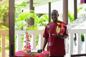 Um homem segurando um tabuleiro com duas bebidas. em White Peacock Resort Mtwapa em Mtwapa