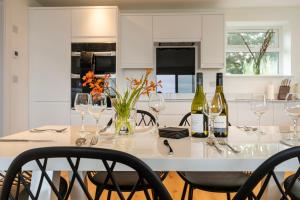a white kitchen with a table with wine bottles and chairs at Lanyon in St Ives