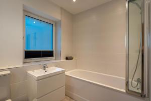 a white bathroom with a sink and a bath tub at Lanyon in St Ives +14 photos
