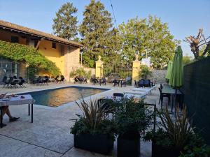 a patio with a pool with tables and chairs and an umbrella at Agriturismo Corte Gaia in Castiglione delle Stiviere