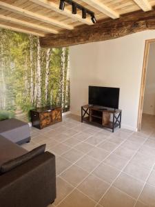 a living room with a couch and a flat screen tv at Gîte des Catalpas in Vollore-Ville