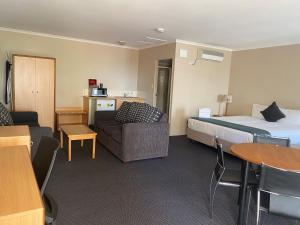 a hotel room with a bed and a couch and a table at Harbour Sails Motor Inn in Gladstone