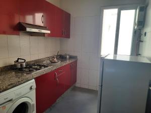 a kitchen with red cabinets and a white refrigerator at MAZAPART in El Jadida