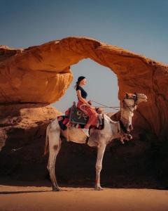 a woman riding on a camel in the desert at Bedouin desert life camp& Jeep tours in Wadi Rum