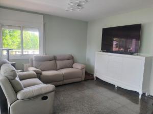 sala de estar con sofá y TV de pantalla plana en Suite en apartartamento compartido en la playa a 20 minutos de Barcelona, en Premiá de Mar