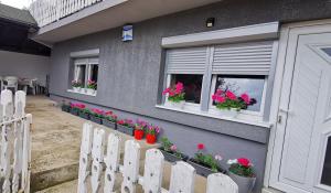 een grijs huis met bloemen in de ramen bij Apartman Delic in Lukavac