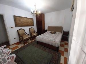 a bedroom with a bed and two chairs and a chandelier at Shery''s home in 6th Of October