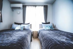 dwa łóżka w pokoju z oknem w obiekcie 青の洞窟and恩納村YAMADA w mieście Yamada