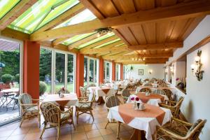 un restaurant avec des tables, des chaises et des fenêtres dans l'établissement Gräfliches Hotel Alte Post, à Bad Birnbach