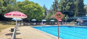 una piscina con una sombrilla roja y una piscina en ג'וליוס סוויטה en Adamit