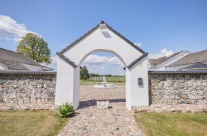 un arco en un patio con una pared de piedra en Arklių Pašto Stotis 