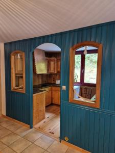 eine Küche mit einer blauen Wand und einem Fenster in der Unterkunft Chalet de la forêt 1 à 6 pers in Saint-Sauveur