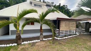 dom z dwoma palmami przed nim w obiekcie Vanakea Beach House w mieście Punaauia