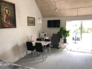 a living room with a table and chairs and a television at Medomgaard in Kibæk