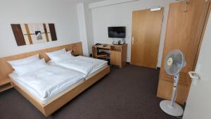 1 dormitorio con 1 cama y escritorio con ventilador en Gästehaus Ziegler en Stuttgart