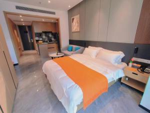 um quarto com uma cama grande e um cobertor laranja em Shi Lai De Executive Apartments em Dongguan