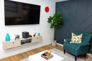 uma sala de estar com uma cadeira azul e uma televisão de ecrã plano em Cozy 2BR Guest Suite in Leduc 12 Mins to YEG em Leduc