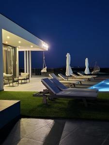 a group of lounge chairs and a swimming pool at night at Villa Porta Novalja in Novalja