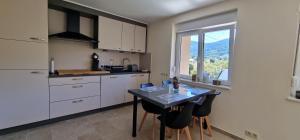 Una cocina con gabinetes blancos y una mesa con sillas. en Gîte moderne et calme avec local séparé pour skis et vélos, en Cornimont