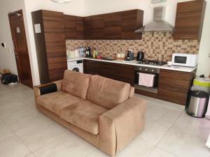 ein Wohnzimmer mit einer braunen Couch in einer Küche in der Unterkunft Hillock Residence Gozo Marsalforn in Marsalforn