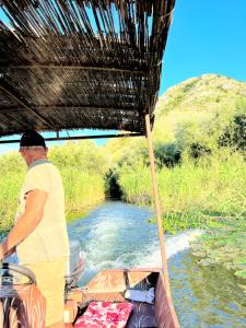 Un uomo in piedi su una barca in un fiume di Ethno village Moraca - Skadar lake a Vranjina