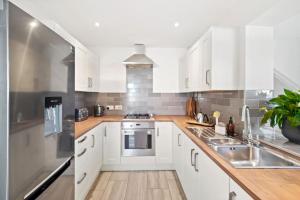 una cucina con armadietti bianchi ed elettrodomestici in acciaio inossidabile di Spacious 2 bedroom house with parking & WiFi a Kent