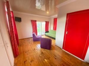 迪迪姆的住宿－Reds Bungalow，客厅配有绿色沙发和紫色椅子