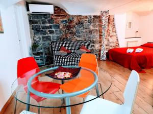 a living room with a glass table and red chairs at Le Grazie Maisons Genova in Genoa
