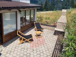 2 chaises assises sur une terrasse à côté d'une maison dans l'établissement Apartman Lejla Vlašić, à Vlašić