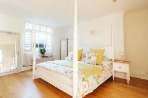 una camera da letto bianca con un letto bianco con cuscini gialli di BRIGHTON BEACH APARTMENT Parking Free On-site a Brighton & Hove