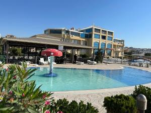 a swimming pool with a red umbrella in front of a building at Aysberq Resort in Baku