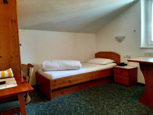 Schlafzimmer mit einem Holzbett und einem Schreibtisch in der Unterkunft Hotel Pörnbacher in Olang