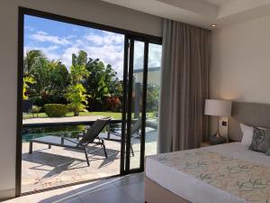 1 dormitorio con cama y vistas a un patio en L'Escapade la Villa de vos prochaines vacances, en Cap Malheureux