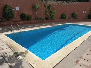 ein großer blauer Pool neben einer Ziegelwand in der Unterkunft Seaview 3 bedroom apartment with swimmingpool in Cañet de Mar