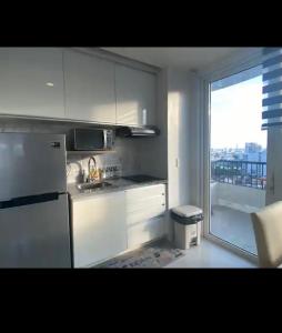 a kitchen with white cabinets and a large window at Calyx Residences 18i in Cebu City