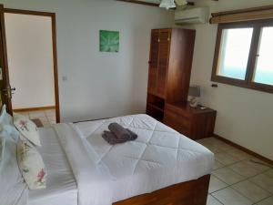 a bedroom with a white bed and a wooden cabinet at La Caze roche Maison d'hôtes in Mahébourg