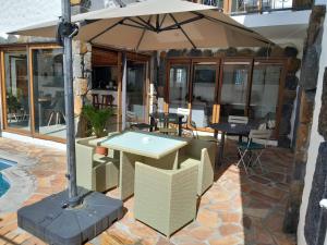 a table and chairs with an umbrella on a patio at La Caze roche Maison d'hôtes in Mahébourg