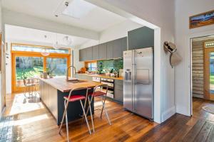 cocina con nevera de acero inoxidable y suelo de madera en 'Questa' Heritage Cottage, en Barnes Bay