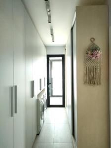 a hallway with white walls and a hallway with pink flowers on the wall at Penthouse panoramic in Chiajna