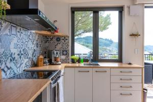 a kitchen with white cabinets and a large window at Firkins Retreat, Picton in Picton