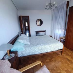 een slaapkamer met een bed en een tafel met een lamp bij Espectaculares Vistas in Santoña