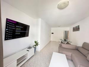 a living room with a couch and a flat screen tv at apartment arrecife beyond in Arrecife