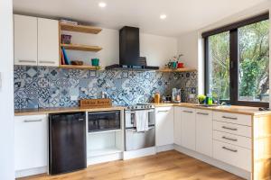 uma cozinha com armários brancos e azulejos azuis e brancos em Firkins Retreat, Picton em Picton