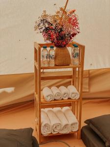 a bamboo shelf with towels and a vase of flowers at MUINE SUN & SEA BEACH ( BOUTIQUE RESORT & GLAMPING) in Mui Ne